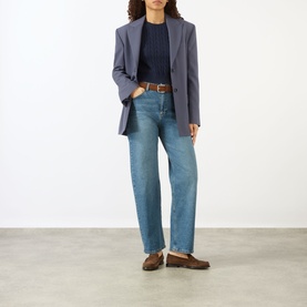 Model wearing Sporty and Rich Dark Navy knitwear top, styled with blue-grey blazer, wide-leg jeans and brown loafers
