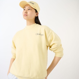 Model wearing Sporty and Rich Almond Navy cotton sweatshirt with script logo, styled with matching cap and light blue trousers