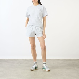 Model wearing Sporty and Rich grey cotton shorts with matching grey T-shirt and green high-top trainers.