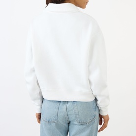 Model wearing Sporty and Rich white sweatshirt, back view, styled with light blue denim jeans.