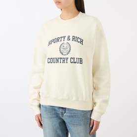 Model wearing Sporty and Rich ecru cotton sweatshirt with navy Country Club graphic print, styled with light blue jeans