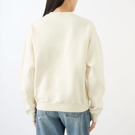 Model wearing Sporty and Rich ecru cotton sweatshirt, back view, styled with light blue jeans.