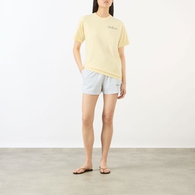 Model wearing Sporty and Rich Almond Navy cotton T-shirt with light blue shorts and flip flops