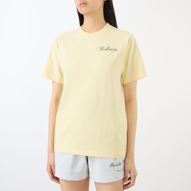 Model wearing Sporty and Rich Almond Navy cotton T-shirt with script chest print, styled with grey shorts.