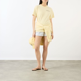 Model wearing Sporty and Rich Almond Navy cotton T-shirt, knotted at waist, styled with light blue shorts and tan sandals