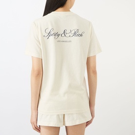 Model wearing Sporty and Rich ecru cotton T-shirt, back view showing script logo print, styled with matching shorts.