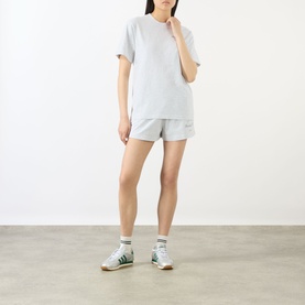 Model wearing Sporty and Rich Heather Grey cotton T-shirt with matching shorts, styled with white ankle socks and green trainers.