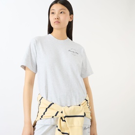 Model wearing Sporty and Rich Heather Grey cotton T-shirt with small chest logo, styled with a yellow striped wrap tied at waist.