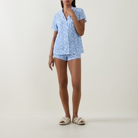 Model wearing Stripe & Stare La Jardin Bleu pyjama shorts set in blue floral print, styled with fluffy cream slippers