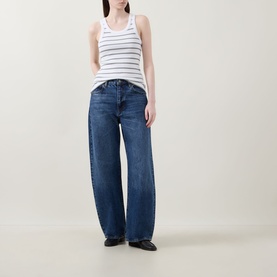 Model wearing Vince Stripe Ribbed Tank Top in white with scoop neck, paired with wide-leg blue jeans and black flat shoes.