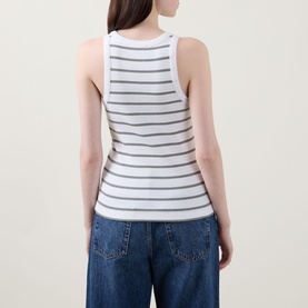 Model wearing Vince Stripe Ribbed Tank Top in white with grey stripes, racer-back style, paired with wide-leg blue jeans.