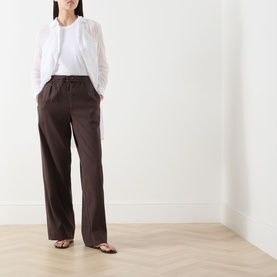 Model wearing Vince Drawstring Summer Trousers in brown linen-blend with wide-leg fit, styled with a white blouse and tan sandals.