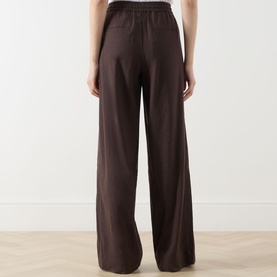 Model wearing Vince Drawstring Summer Trousers in brown, showing elasticated waistband and wide-leg linen-blend silhouette, rear view