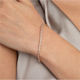 Model with Astrid & Miyu gold tennis bracelet featuring row of clear crystal stones in rose gold-tone setting