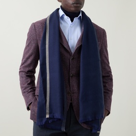 Model with B Cucinelli Contrast-Trim Frayed Scarf in blue, wrap-around style with grey contrast trim and frayed edges, styled with burgundy blazer