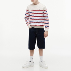 Model wearing cream striped knit jumper with red and blue stripes, styled with navy shorts, white socks and white trainers