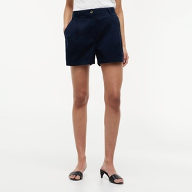 Model wearing navy tailored shorts with button fastening, styled with black heeled mules