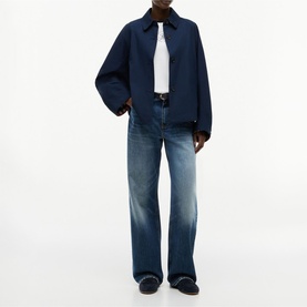 Model wearing Tommy Hilfiger Dark Night Navy jacket with white top, blue wide-leg jeans and dark loafers