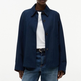 Model wearing Tommy Hilfiger Dark Night Navy button-front jacket, styled with white graphic tee and blue jeans