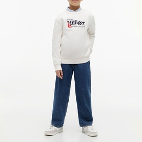 Model wearing Tommy Hilfiger cream logo hoodie, styled with blue wide-leg jeans and white trainers