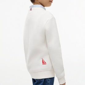 Model wearing white zip-neck sweatshirt with red sailboat embroidery, styled with a light blue collared shirt underneath