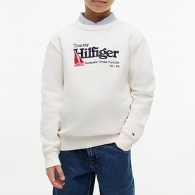 Model wearing Tommy Hilfiger cream logo graphic sweatshirt, styled with blue chambray shirt and jeans