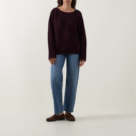 Model wearing Elena Miro must knitwear jumper with wide sleeves and boat neck, styled with blue straight-leg jeans and brown loafers.