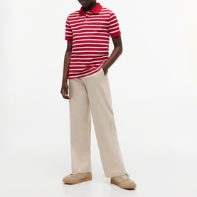 Model wearing red and white striped polo shirt with wide-leg beige trousers and tan loafers.