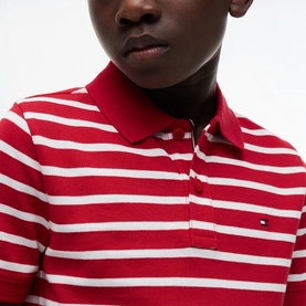 Model wearing red and white striped Tommy Hilfiger polo shirt with collar and button placket, close-up chest detail view