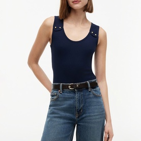 Model wearing Tommy Hilfiger Dark Night Navy sleeveless bodysuit with gold stud shoulder detail, styled with blue wide-leg jeans and a belt.