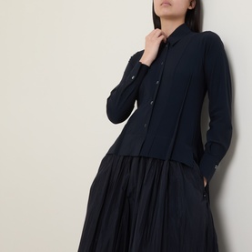 Model wearing HIGH Habit Shirt Dress in navy, showing raised shirt hem over crinkled midi skirt, turned-down collar and front button closure