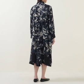Model wearing HIGH Skive Printed Tie-Front Dress in blue abstract print, midi length with asymmetric flared skirt and long sleeves, back view