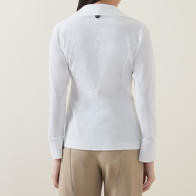 Model wearing HIGH Behave Slim Shirt in white, back view showing shaping seams, raw-cut hem, and fitted long sleeves. Styled with beige trousers.