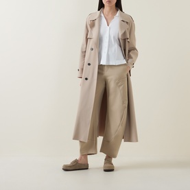 Model wearing HIGH Behave Slim Shirt in white with V-neckline, styled with beige trench coat, wide-leg trousers and loafers.