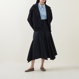Model wearing HIGH Helix Asymmetric Pinstripe Skirt in navy, midi length with asymmetric hem, styled with cropped jacket and blue shirt.