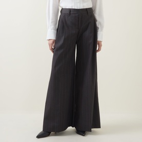 Model wearing HIGH Doff Pleated Pinstripe Trousers in dark grey with wide-leg silhouette and front pleats, styled with a white shirt and black shoes.