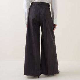 Model wearing HIGH Doff Pleated Pinstripe Trousers in dark grey, wide-leg silhouette with front pleats and pressed creases, styled with a white shirt