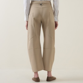 Model wearing HIGH Greece Barrell Leg Boyfriend Fit Trousers in beige, rear view showing seam-wrapped legs and waistband detail