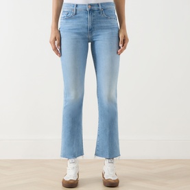 Model wearing Mother Crop Boot jeans in Room Service light blue wash, cropped flare leg with raw hem, styled with white trainers