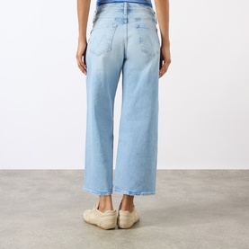 Model wearing Mother The Dodger Ankle Straight Jeans in light wash, showing rear view with wide-leg cropped fit and tobacco stitching detail.