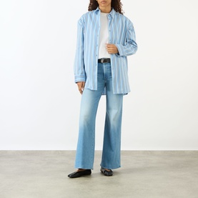 Model wearing Mother The Hustler High-Rise Wide Leg Jeans in Room Service light blue denim, styled with a striped oversized shirt and black loafers.