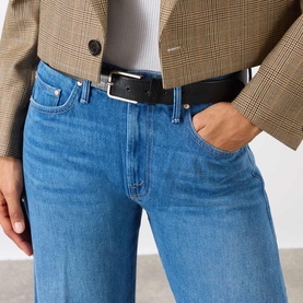 Model wearing Mother The Lasso Sneak Wide-Leg Jeans in mid wash blue with black belt, styled with a plaid blazer and white top.
