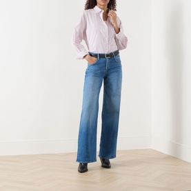 Model wearing Mother Wide Leg jeans in Kissing The Caddy blue denim, styled with a pink shirt and black loafers