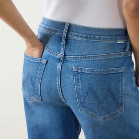 Model wearing Mother Wide Leg jeans in Kissing The Caddy mid-blue denim, close-up of back pockets with M-stitch detail.