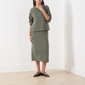 Model wearing Part Two Beetle Sweat Top in khaki green, styled with matching midi skirt and black flat mules.