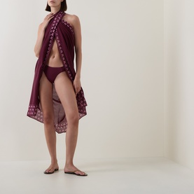 Model wearing Seafolly Dark Burgundy Bikini Brief, styled with a matching burgundy embroidered sarong wrap and flat sandals.
