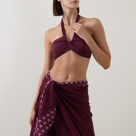 Model wearing Seafolly dark burgundy halterneck bikini top with twisted front detail, styled with matching burgundy sarong skirt