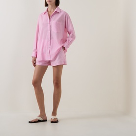 Model wearing Seafolly Light Pop Pink cotton cover-up shirt and matching shorts, styled with black flat sandals