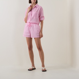 Model wearing Seafolly Light Pop Pink cotton cover-up shirt and matching shorts, styled with white flat sandals