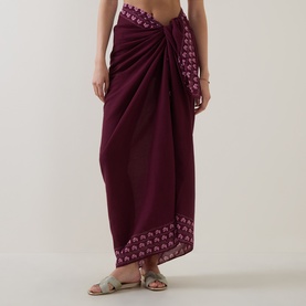 Model wearing Seafolly Dark Burgundy cotton sarong, tied at waist, with embroidered border trim, styled with silver sandals